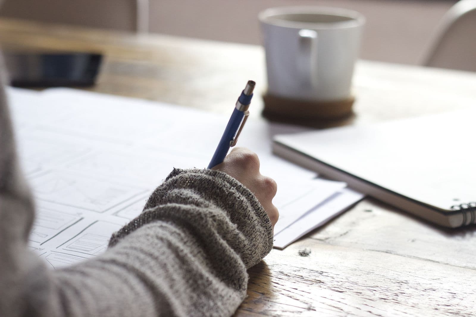 A designer sketching wireframes with a pen