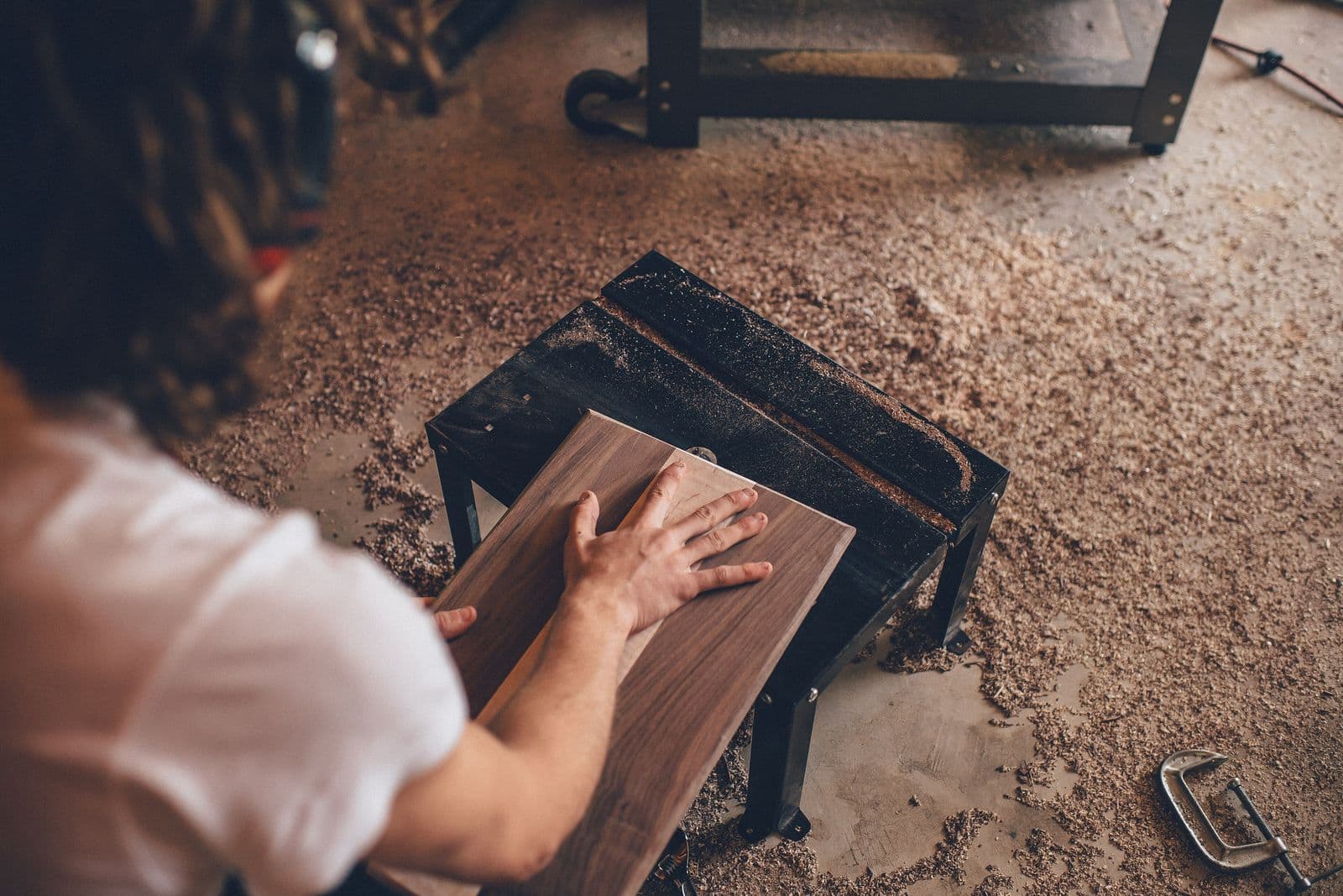 A woodworker sanding a wooden board in a workshop